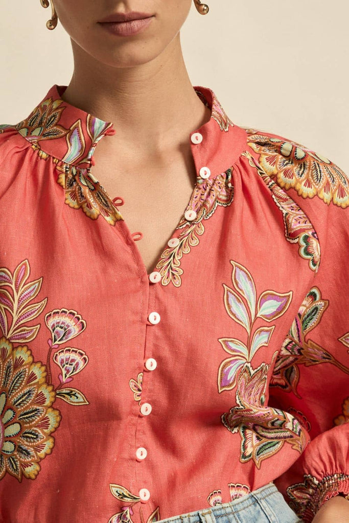Close-up of a red floral embroidered blouse with a beige background