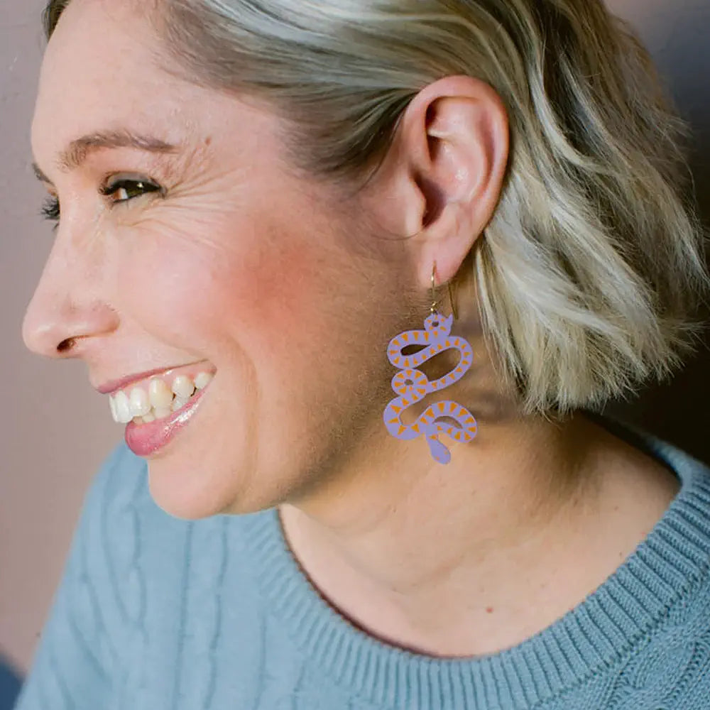 Woman wearing snake-shaped earrings with a blurred background