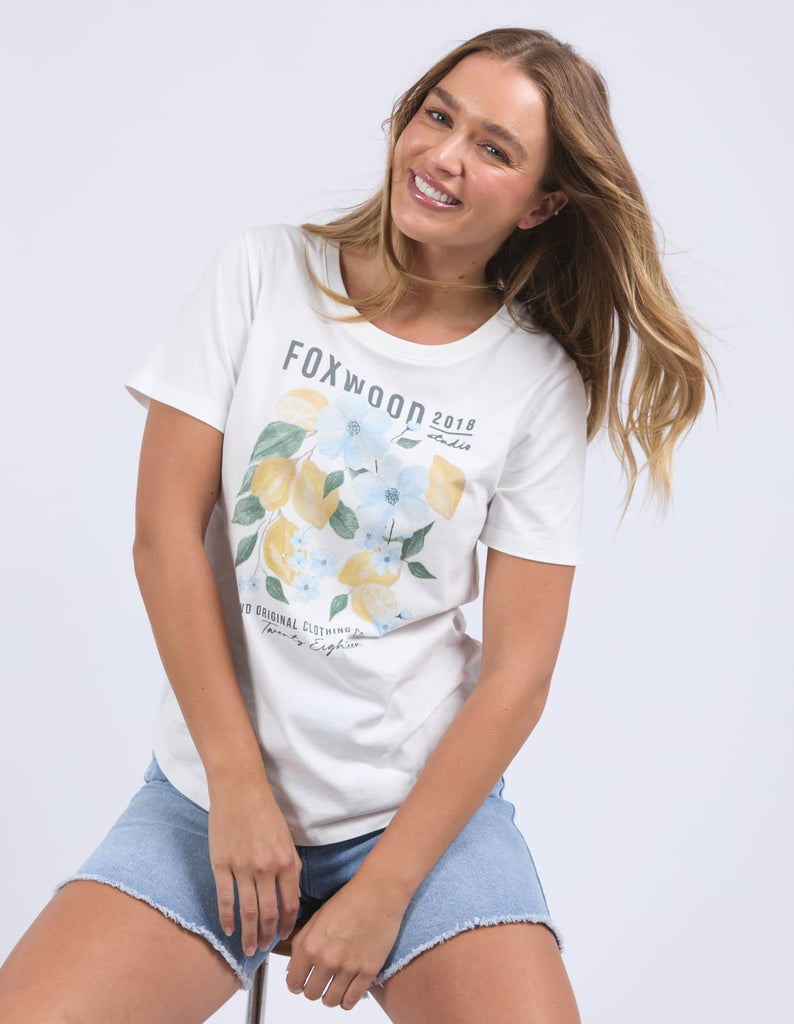 Woman wearing a white t-shirt with floral design and text on a plain background