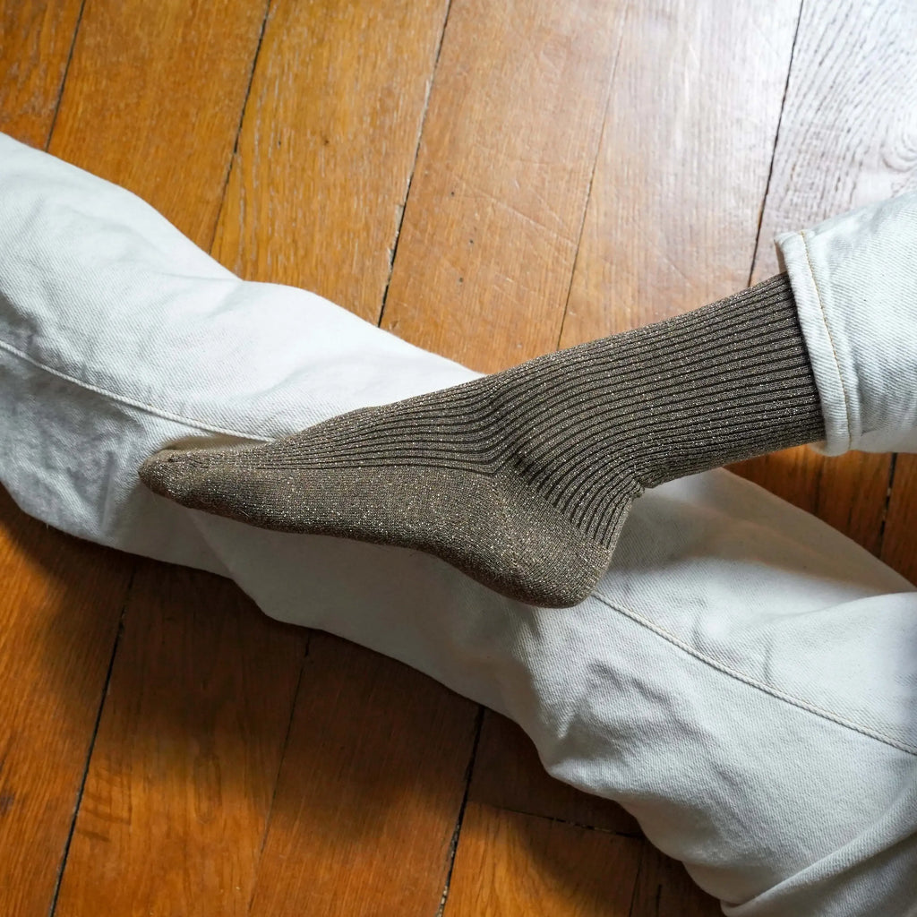 Person wearing brown socks and light-colored pants on a wooden floor