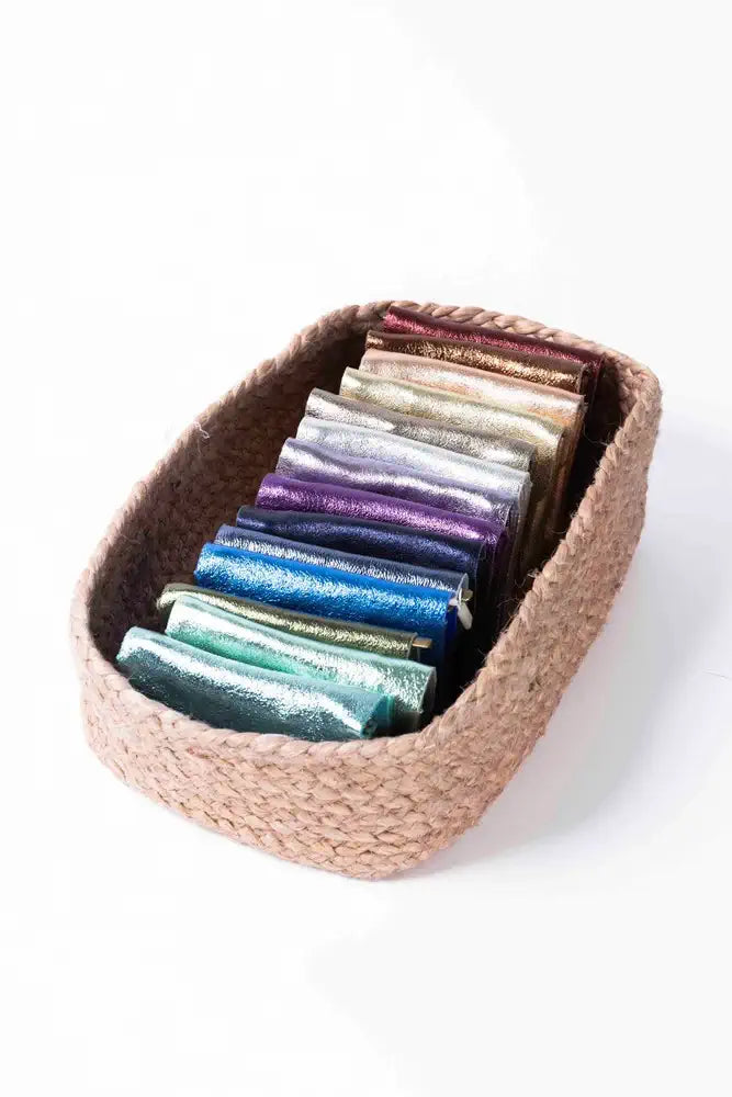 Woven basket with colorful rolled-up towels on a white background
