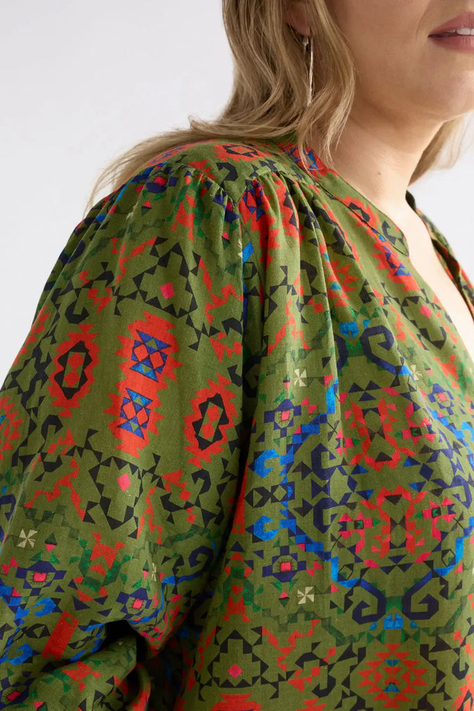Green patterned blouse with long sleeves on a plain background