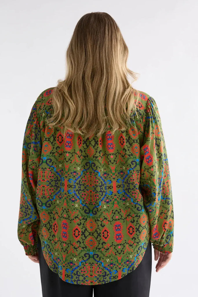 Person wearing a colorful patterned blouse on a white background