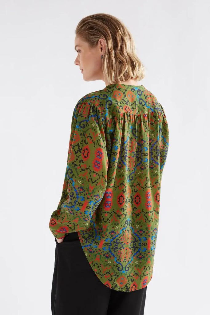 Woman wearing a colorful patterned blouse on a white background