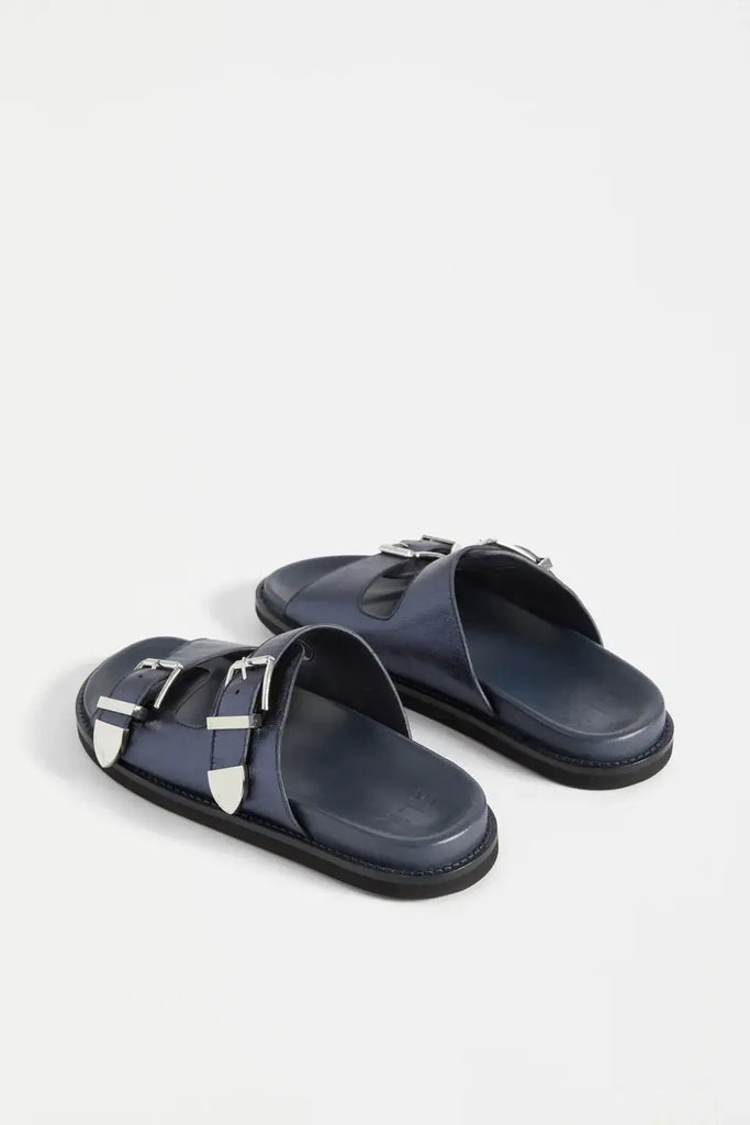 Pair of navy sandals with metallic accents on a white background