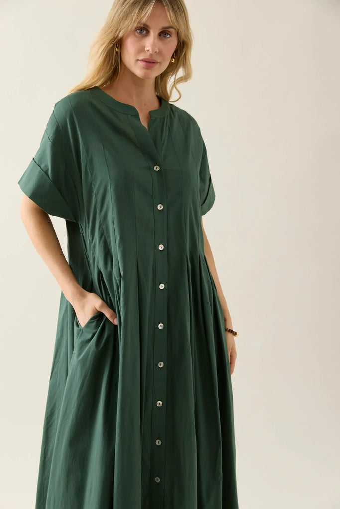 Woman wearing a green dress with button details on a plain background