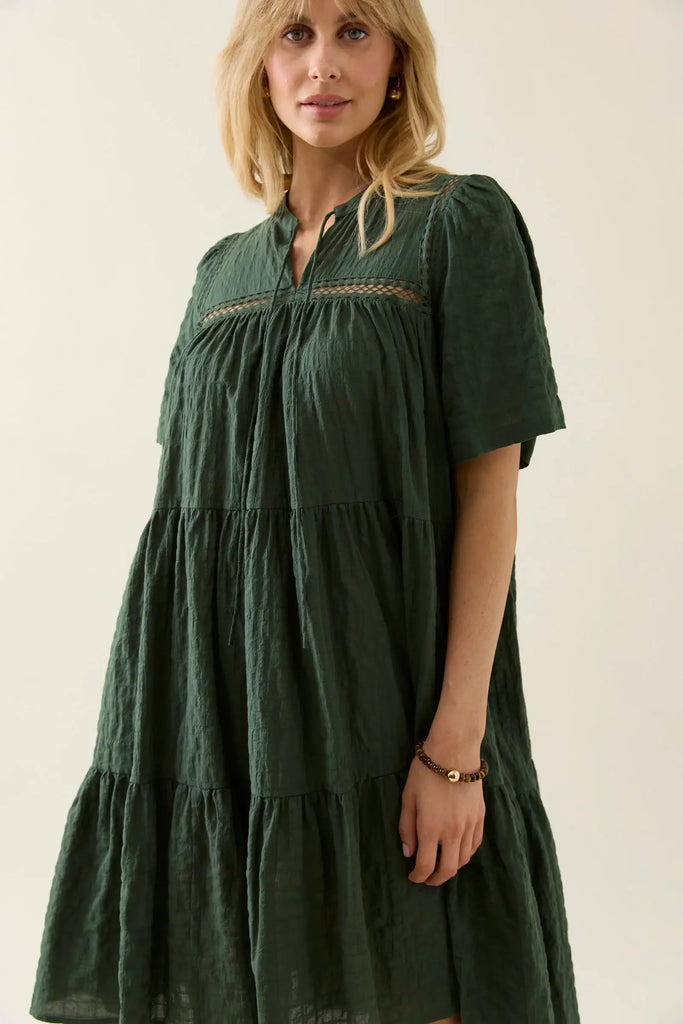Woman wearing a green dress with a plain background