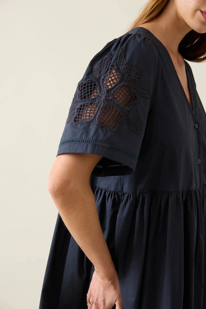Navy blue dress with lace detailing on sleeves against a neutral background