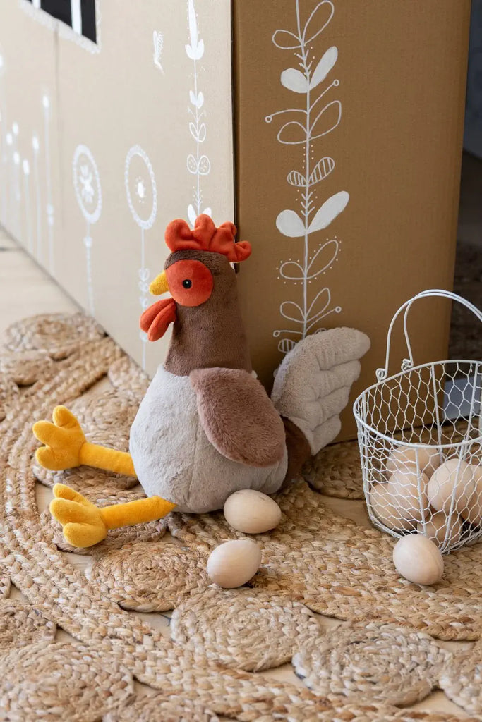 Plush chicken toy with eggs on a textured surface